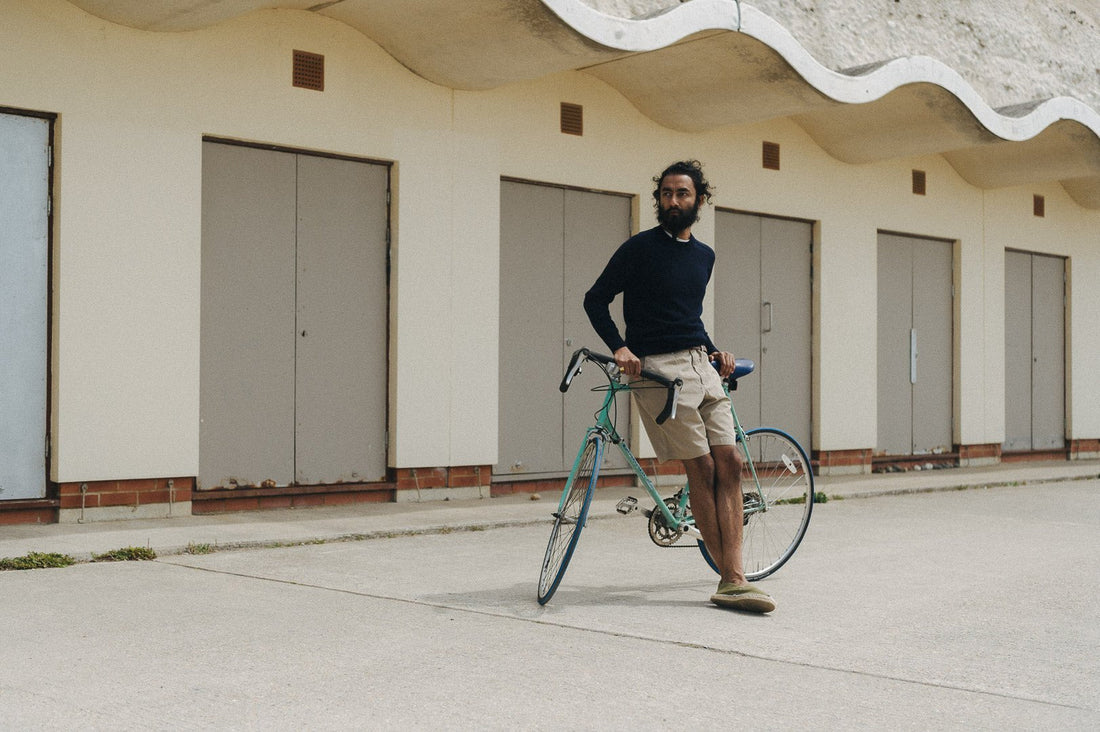 Man leans against a vintage bike wearing shorts and Malloch's Easton Merino Sweater